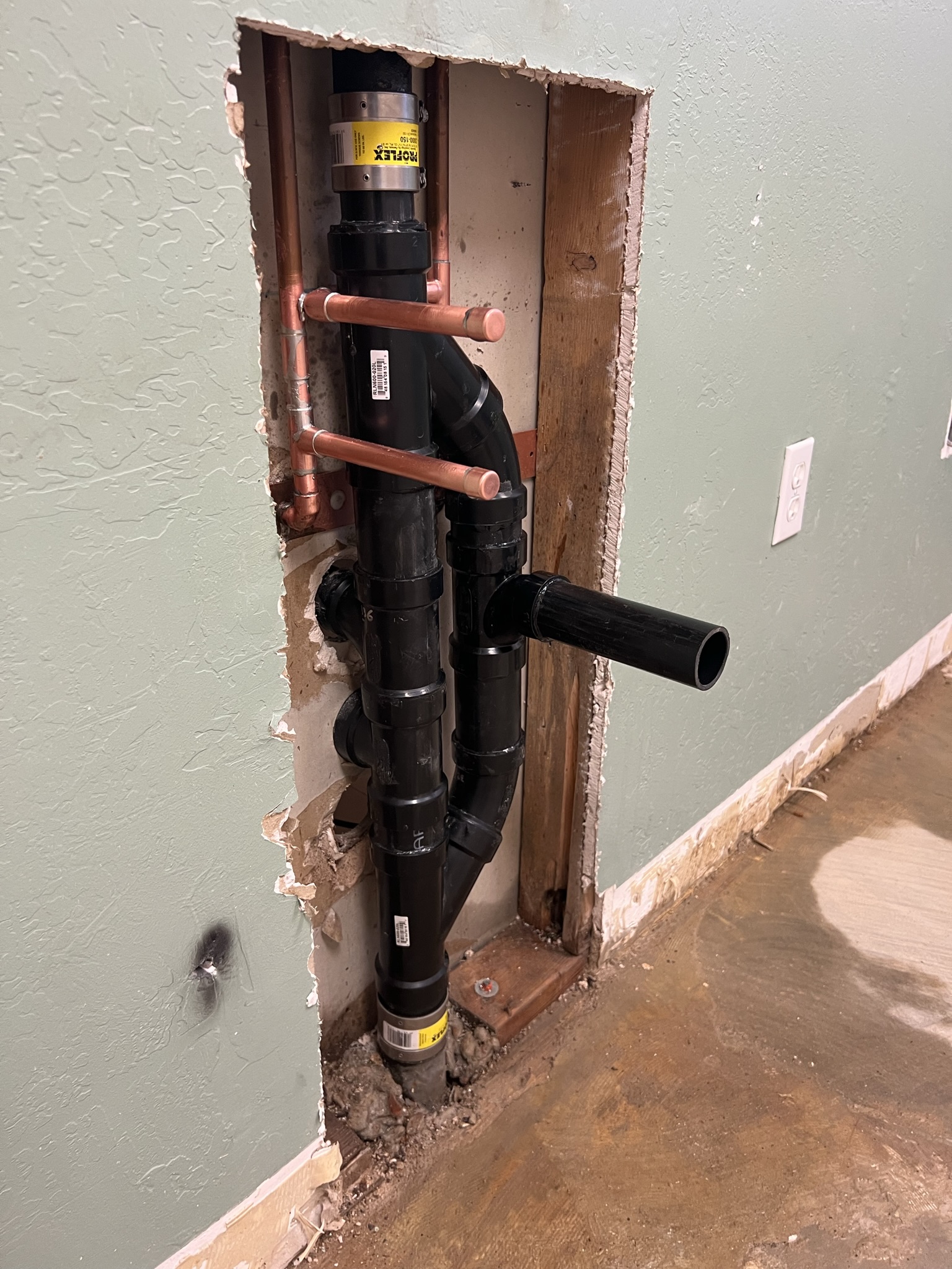 Wall cutout showing copper and ABS pipe repair